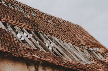 Roof with damaged and missing shingles exposing wood decking beneath