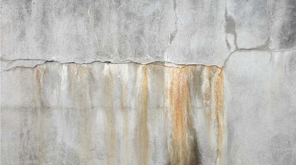 Cracked concrete wall with rust and water staining from moisture intrusion